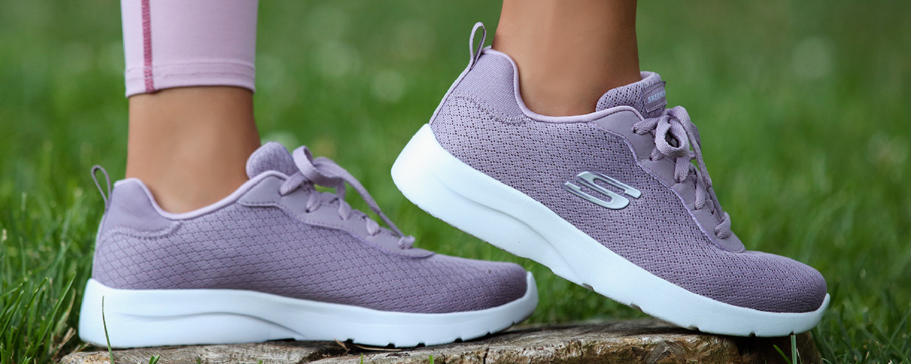 Naisen jaloissa vaalean liilat Skechers kengät