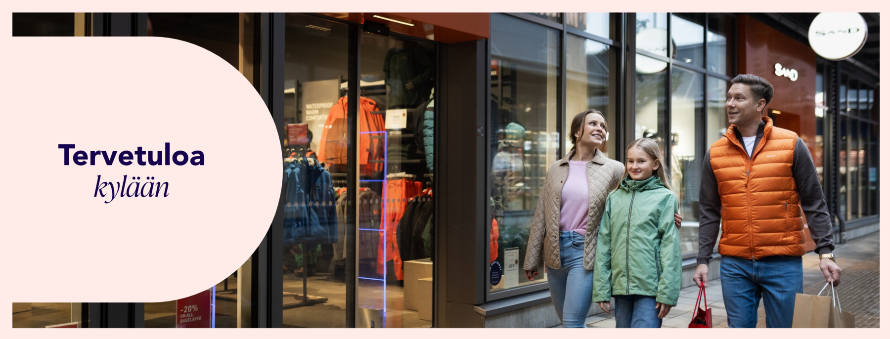 Perhe kävelee syksyisellä Helsinki Outletin ostoskadulla. Kuvassa teksti ”Tervetuloa kylään”