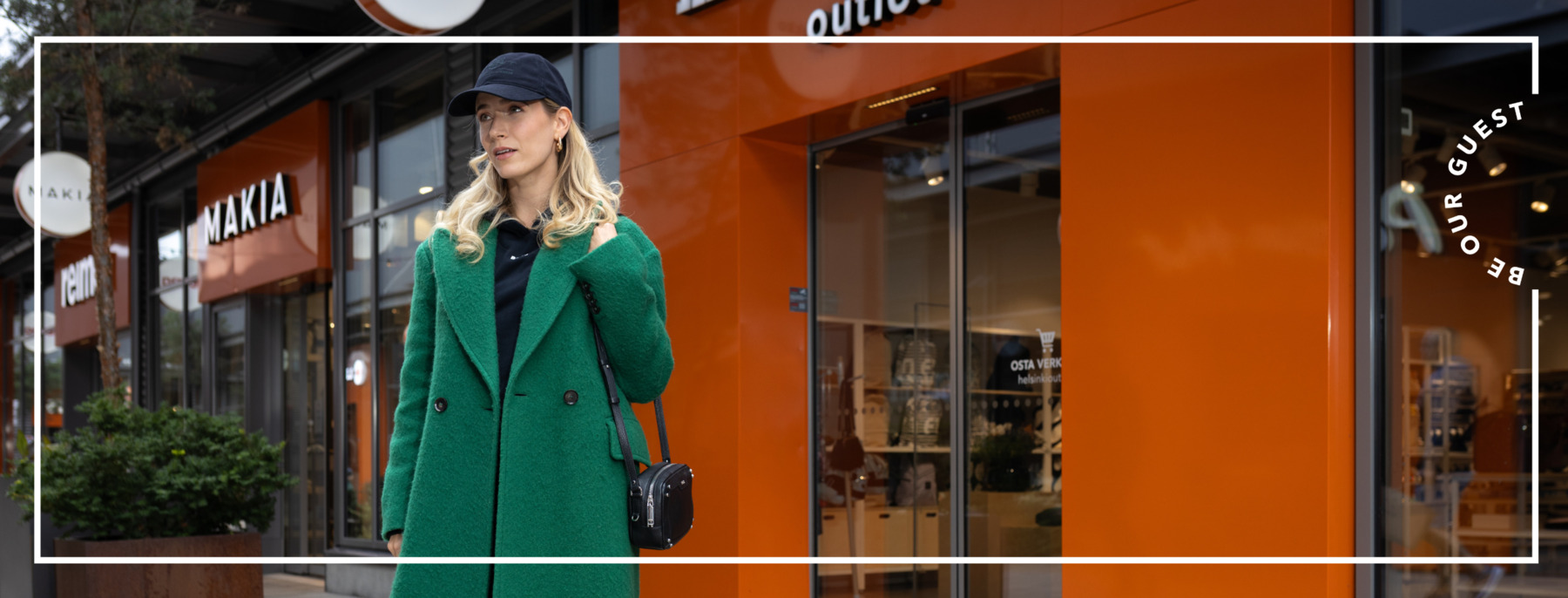 A woman wearing a green jacket and a black cap is shopping in the village on a sunny autumn day