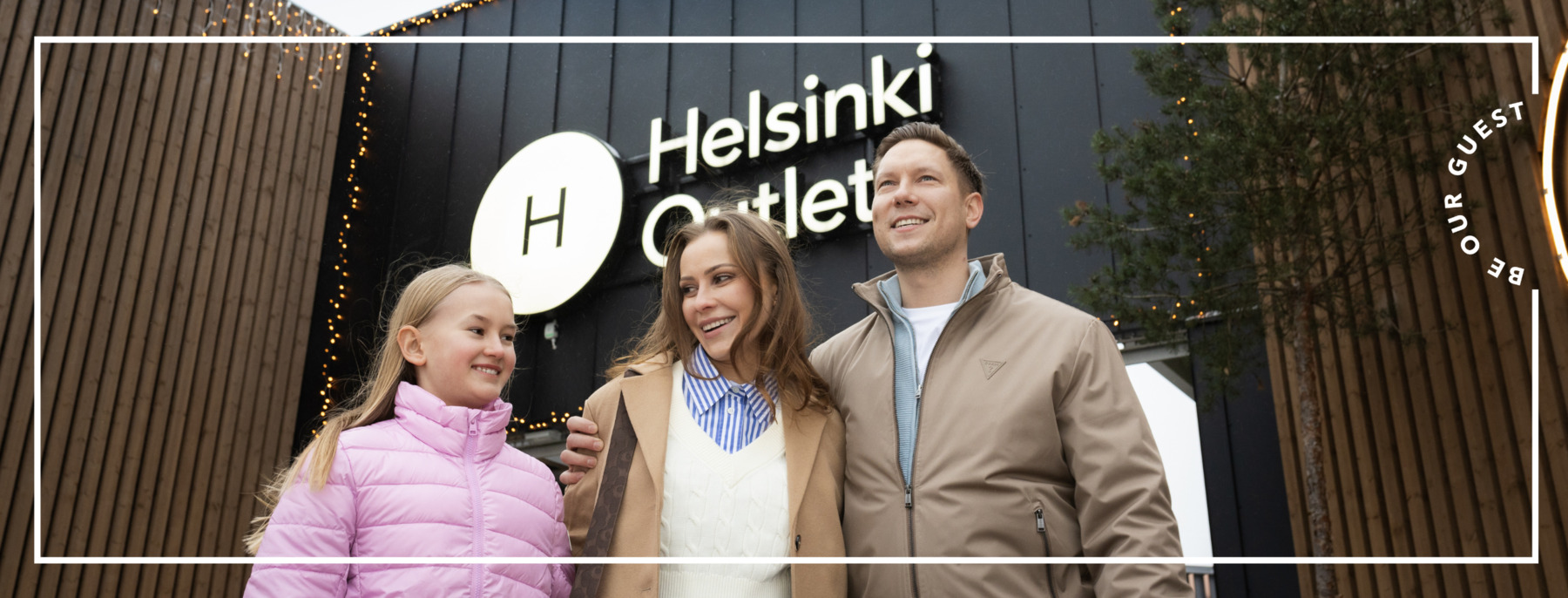 A family (mom, dad and daughter) standing at the entrance of a shopping village
